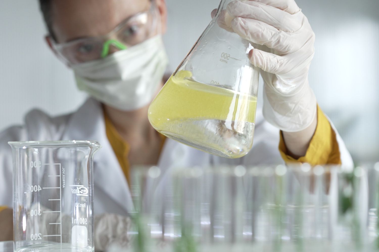 gepco-formacion-una-cientifica-investigadora-con-guantes-de-proteccion-blancos-esta-sacudiendo-una-solucion-quimica-amarilla-dentro-de-un-frasco-erlenmeyer-en-un-laboratorio